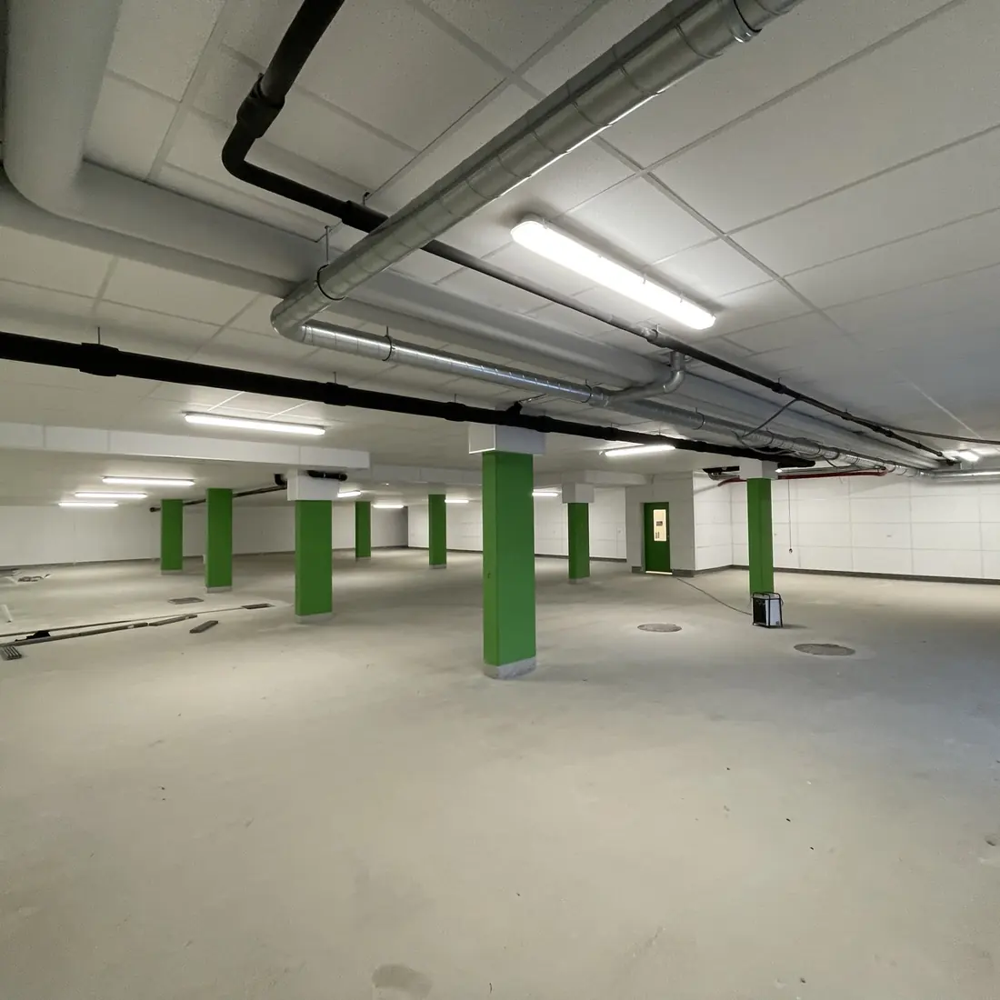 Tiefgarage im Bauvorhaben Bergblick mit gedämmter Decke und grün gestrichenen Stützen