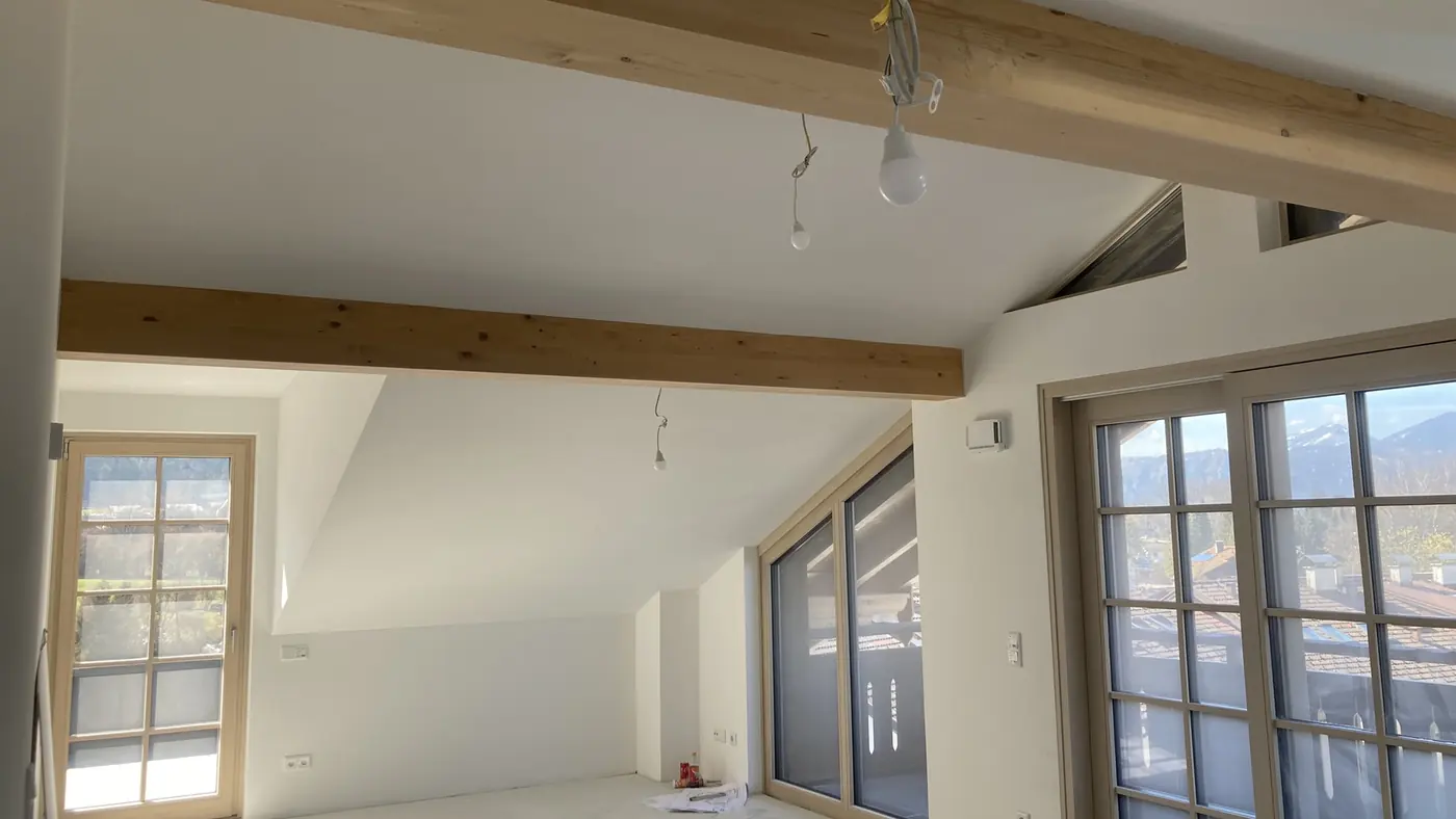 Dachgeschoss mit sichtbaren Holzbalken und Fensterfront, Bauvorhaben Bergblick in Salzburg